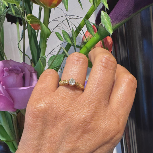 A yellow gold single stone diamond ring with a decorative shank, modelled on a hand