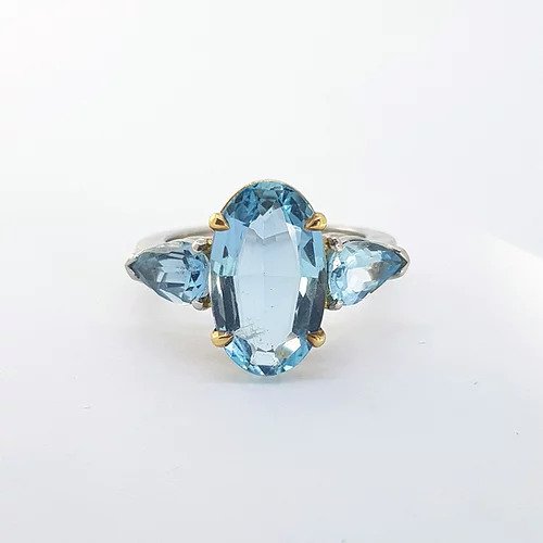 Aquamarine Three Stone Ring; central oval faceted aquamarine, four-claw set in 18ct yellow gold, flanked by pear-cut aquamarines, 6.50 carats, to a plain platinum shank