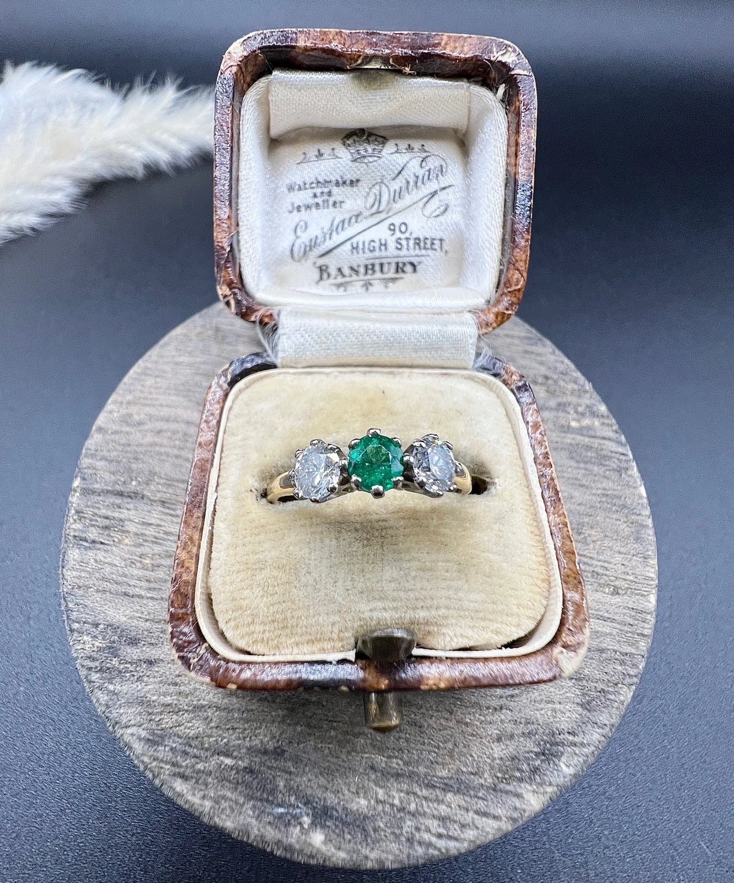 A three stone emerald and diamond ring in yellow gold and platinum, in an antique ring box