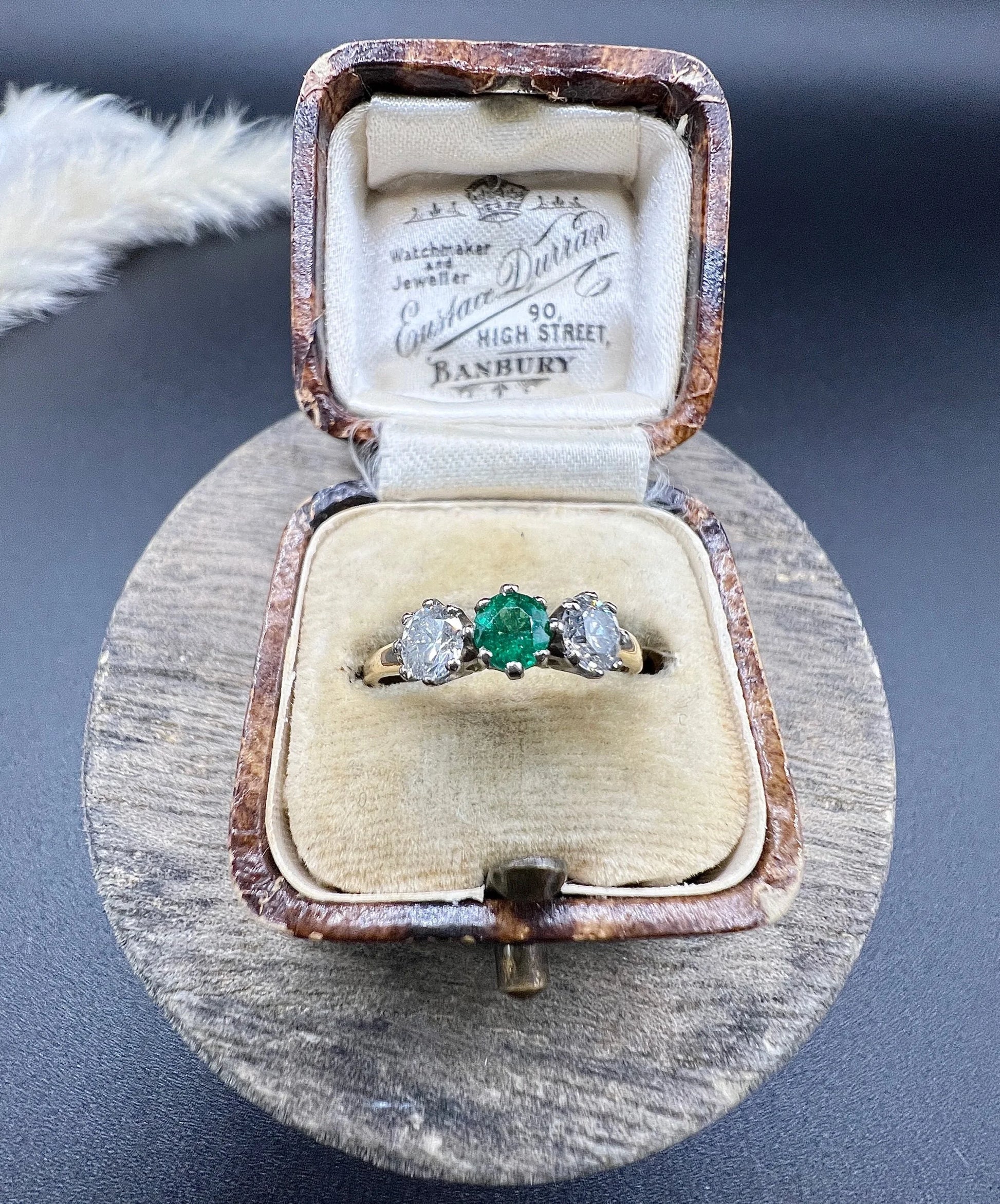 A three stone emerald and diamond ring in yellow gold and platinum, in an antique ring box