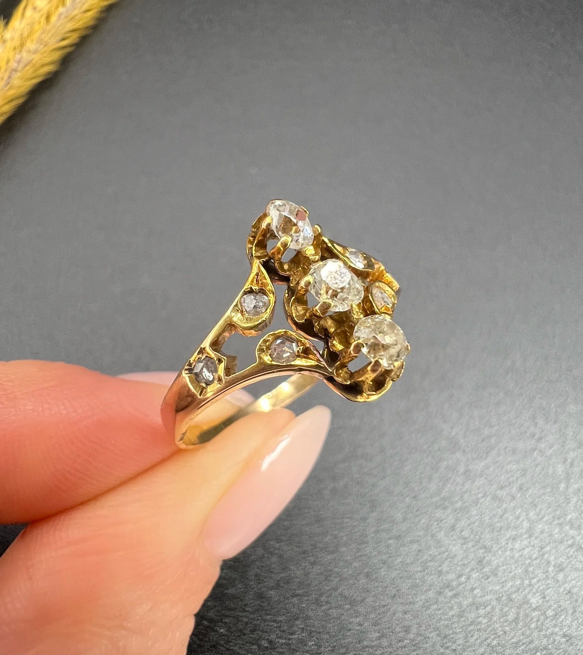 An antique old cut diamond ring in yellow gold, held in a hand