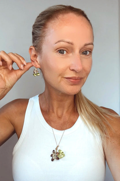 Gold and enamel diamond flower pendant and earring modelled by a lady wearing a white top