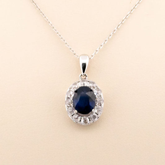 An oval sapphire and diamond cluster pendant in white gold, on a white gold chain