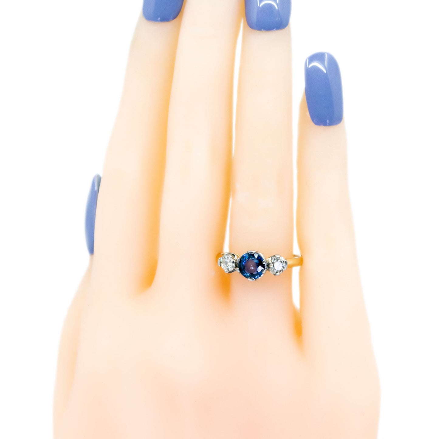 A three stone sapphire and diamond ring in yellow and white gold, modelled on a hand