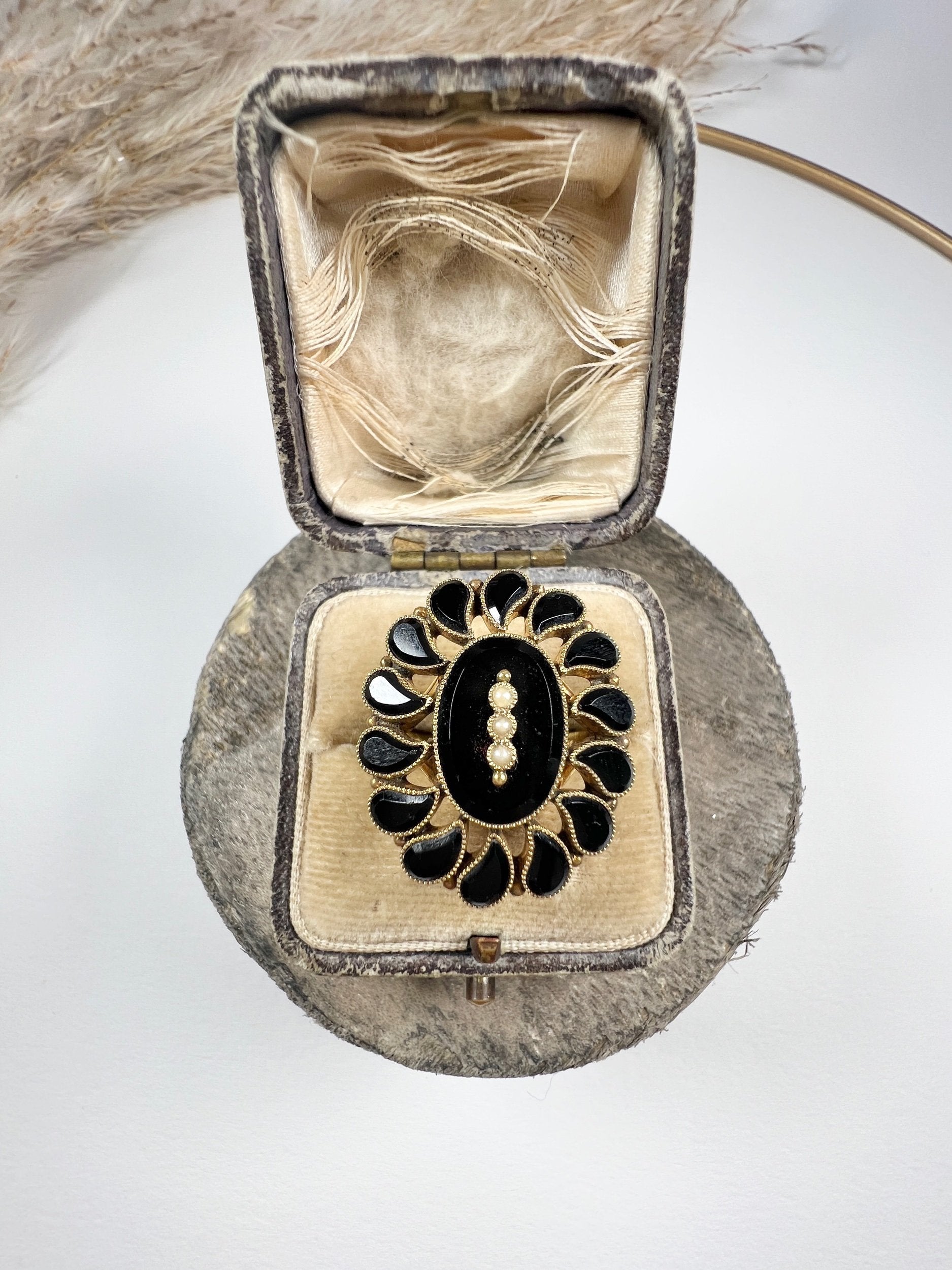 A black onyx and seed pearl fancy halo cluster ring in yellow gold, in a ring box