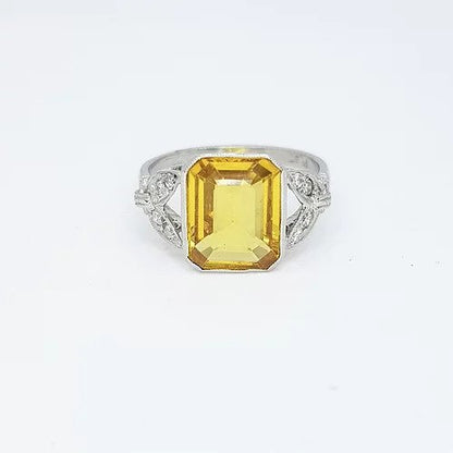 Emerald Cut Yellow Sapphire, Diamond and Platinum Ring; 3.20ct emerald-cut yellow sapphire accented with 0.15cts diamond set shoulders in fleur-de-lis deign