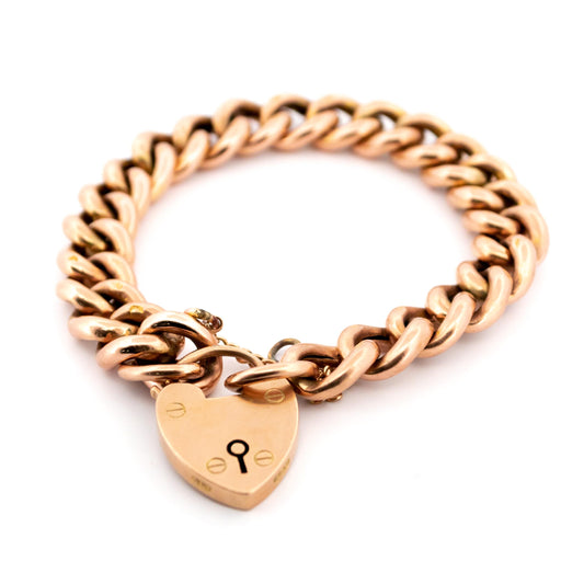A yellow gold curb link bracelet with heart padlock clasp