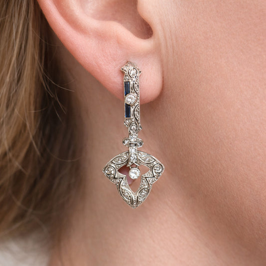 A diamond and sapphire drop earring, modelled in an ear