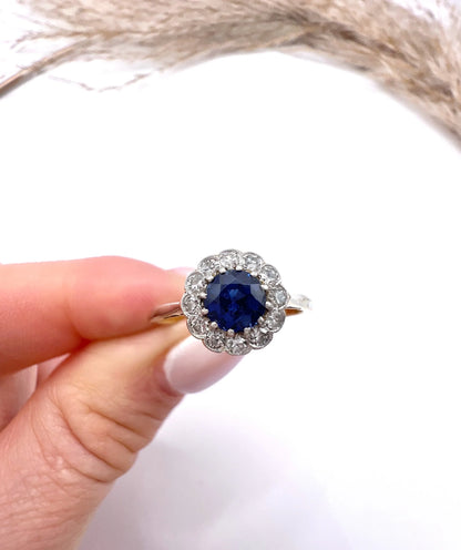 A sapphire and diamond flower cluster ring in yellow gold and platinum, held in a hand