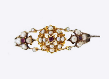 Antique Edwardian Pearl and Ruby Bangle; A delicate Edwardian bangle set with pearl clusters featuring central rubies. Marked for 15ct yellow gold.