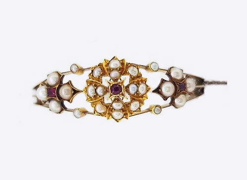 Antique Edwardian Pearl and Ruby Bangle; A delicate Edwardian bangle set with pearl clusters featuring central rubies. Marked for 15ct yellow gold.