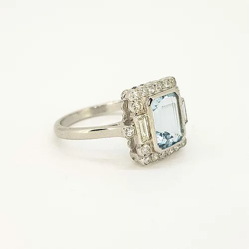 Aquamarine and Diamond Cluster Ring; emerald-cut aquamarine surrounded by round-cut diamonds, baguette-cut diamond set shoulders, in 18ct white gold