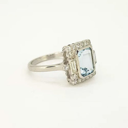 Aquamarine and Diamond Cluster Ring; emerald-cut aquamarine surrounded by round-cut diamonds, baguette-cut diamond set shoulders, in 18ct white gold