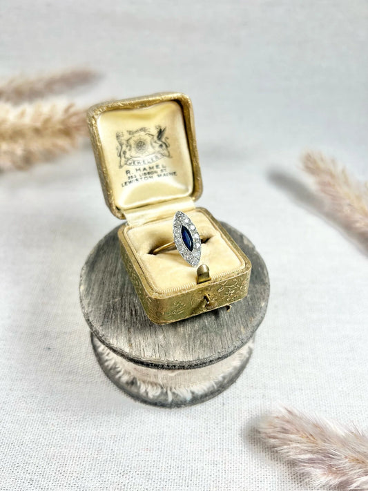 A navette shaped sapphire and diamond cluster ring in yellow gold and platinum, in an antique ring box