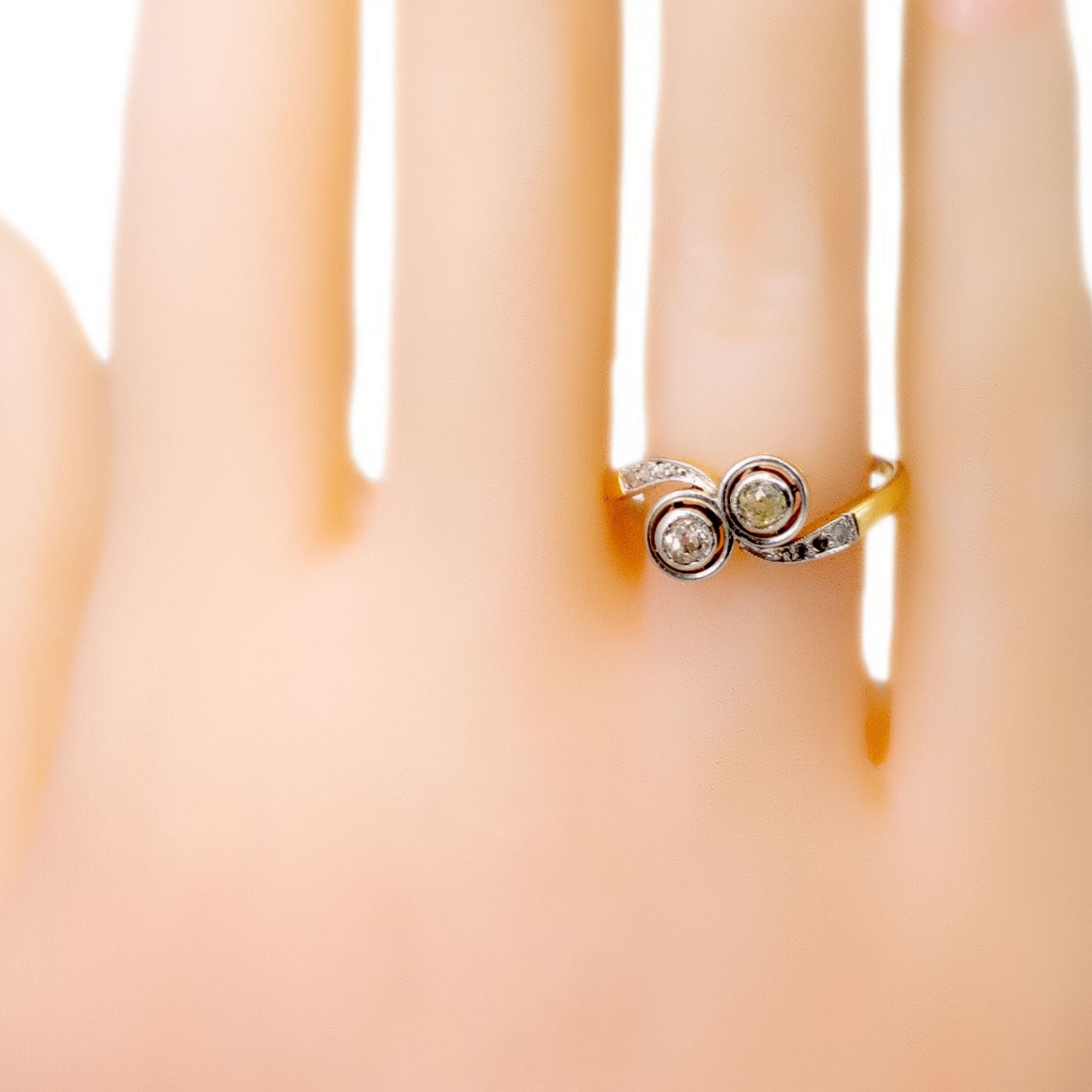 A two stone diamond crossover ring in yellow and white gold, modelled on a hand