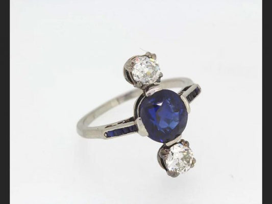 Art Deco Natural Sapphire and Diamond Ring; Central round cut natural sapphire flanked by two round cut diamonds, square cut sapphire shoulders, c.1920