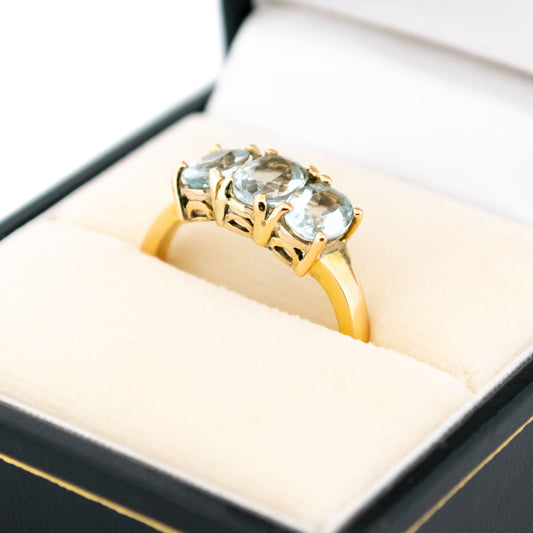 A three stone oval aquamarine ring in yellow gold, in a ring box