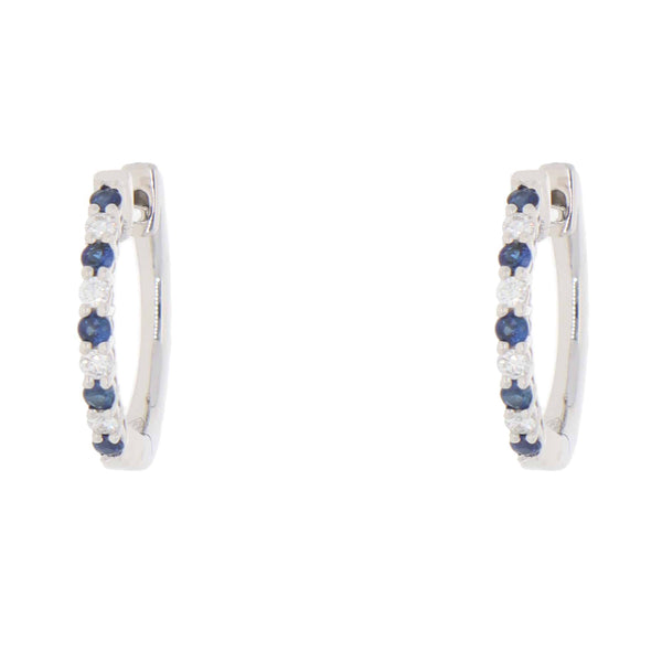 A pair of white gold hoop earrings set with round sapphires and diamonds, on a white background