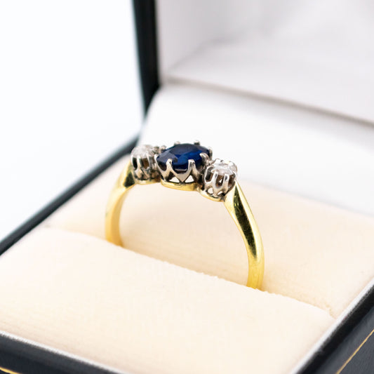 A three stone sapphire and diamond ring in gold and silver, in a ring box