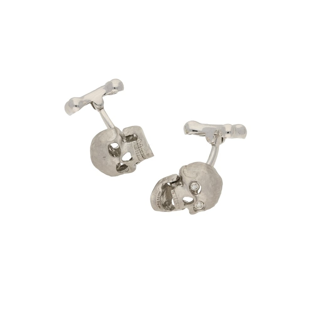 A pair of white gold skull cufflinks with diamond eyes, on a white background