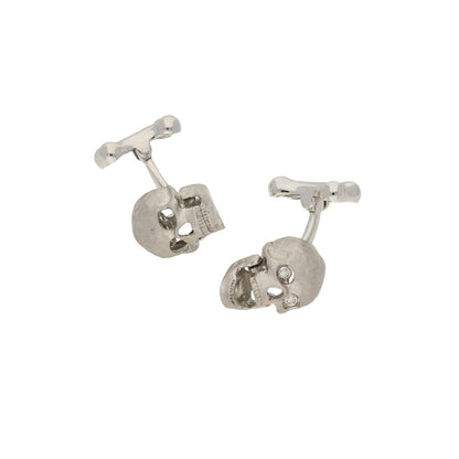 A pair of white gold skull cufflinks with diamond eyes, on a white background