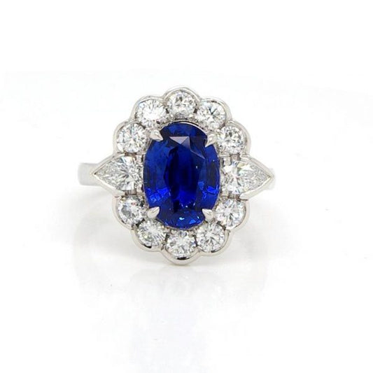 Edwardian Style Sapphire, Diamond and Platinum Oval Cluster Ring; central 2.98ct oval faceted sapphire within a surround of 1.10cts collet-set brilliant cut diamonds, with a trilliant cut diamond to each shoulder