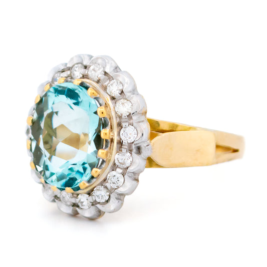 An aquamarine and diamond oval cluster ring in yellow and white gold