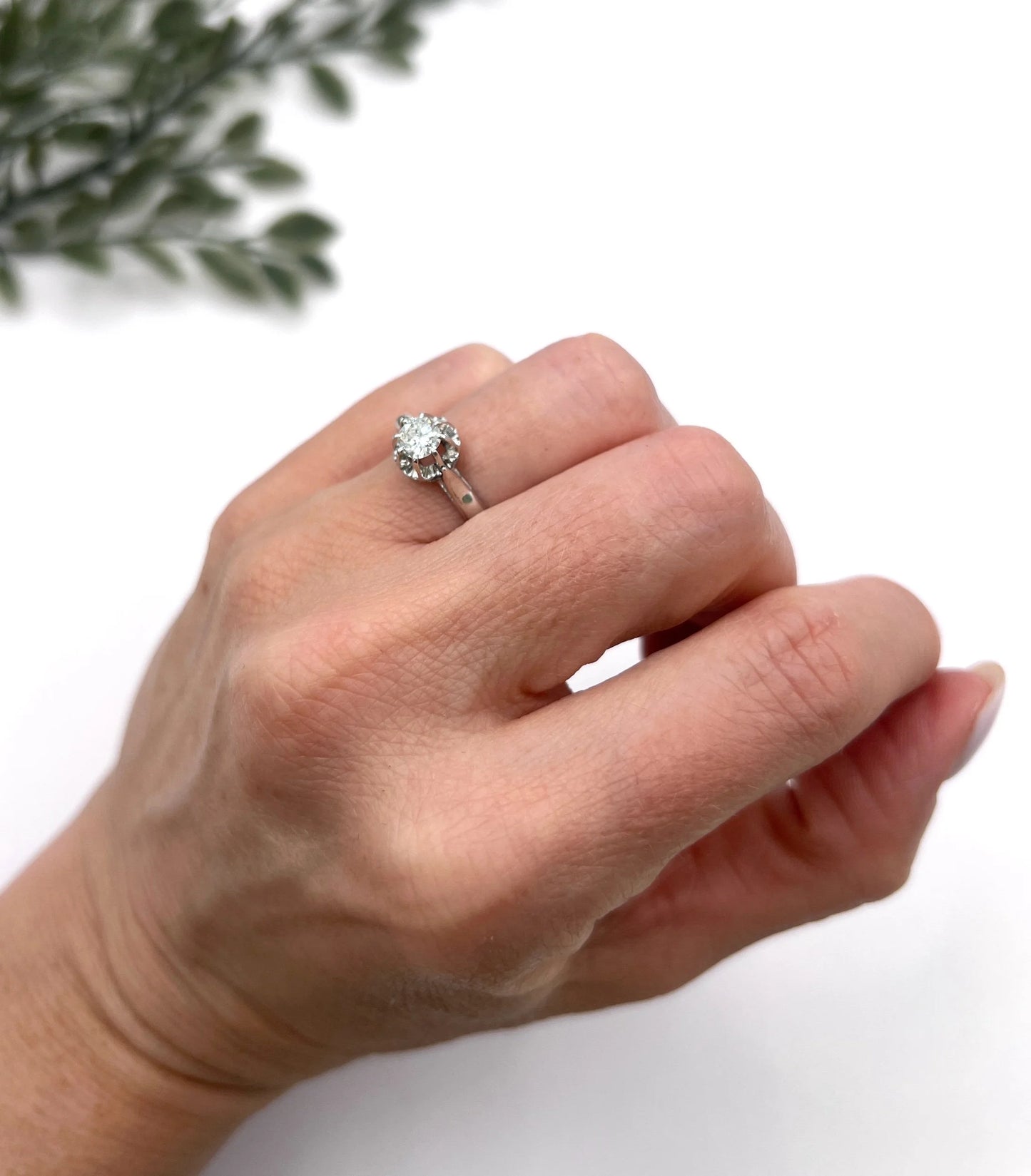 A solitaire round diamond ring in white gold, modelled on a hand