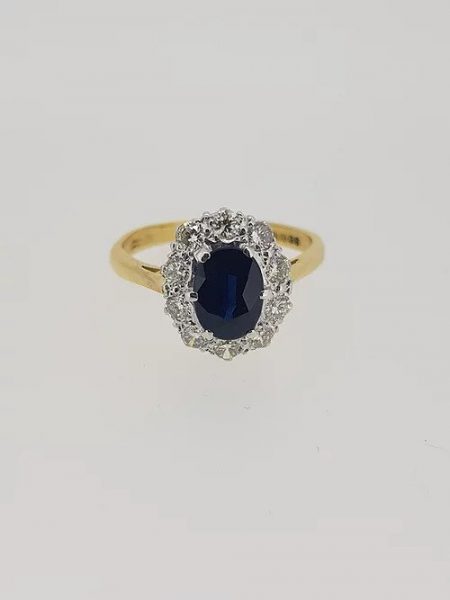 Vintage Sapphire and Diamond Cluster Ring; central oval sapphire within a diamond surround, in 18ct gold, Circa 1970s
