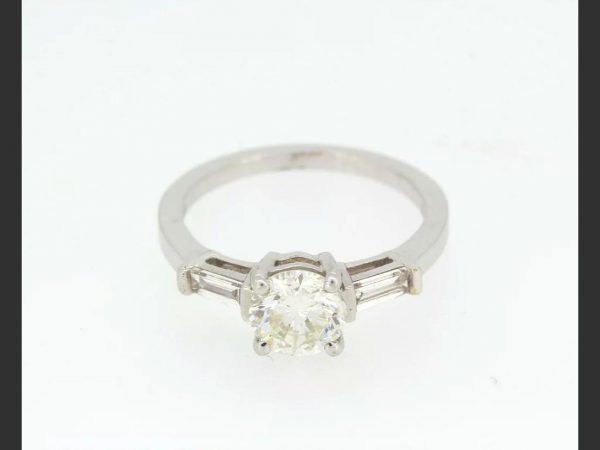 Solitaire Diamond Ring; central 1.23ct round cut diamond, flanked by baguette shoulders totaling 0.33ct, detailed 750, 18ct white gold