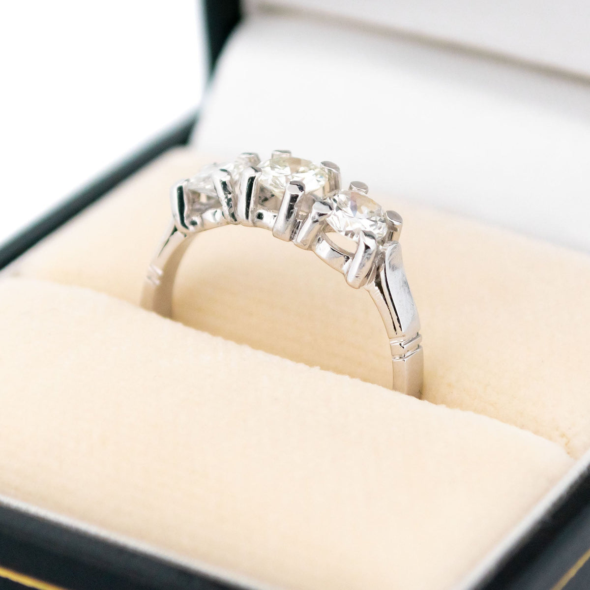 A three stone round diamond ring claw set in platinum, in a ring box