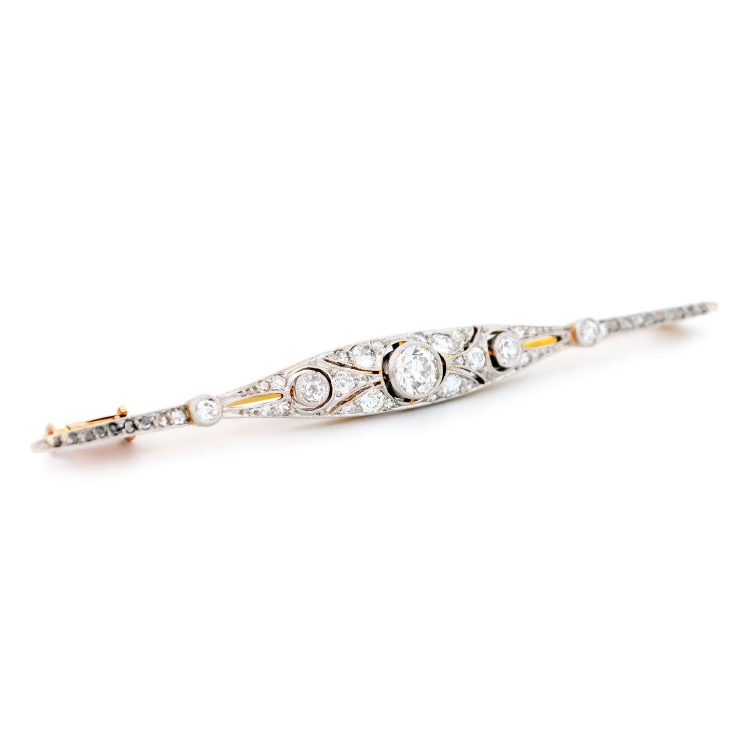 A diamond bar brooch in gold and platinum, on a white background