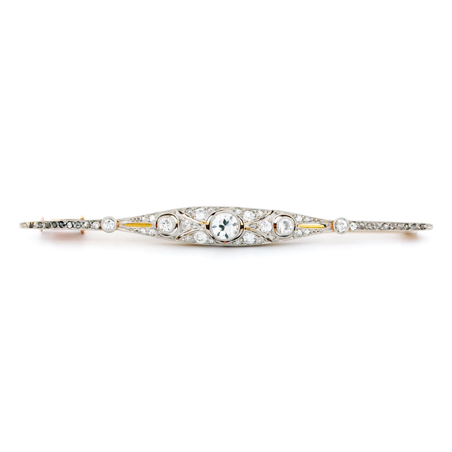 A diamond bar brooch in gold and platinum, on a white background