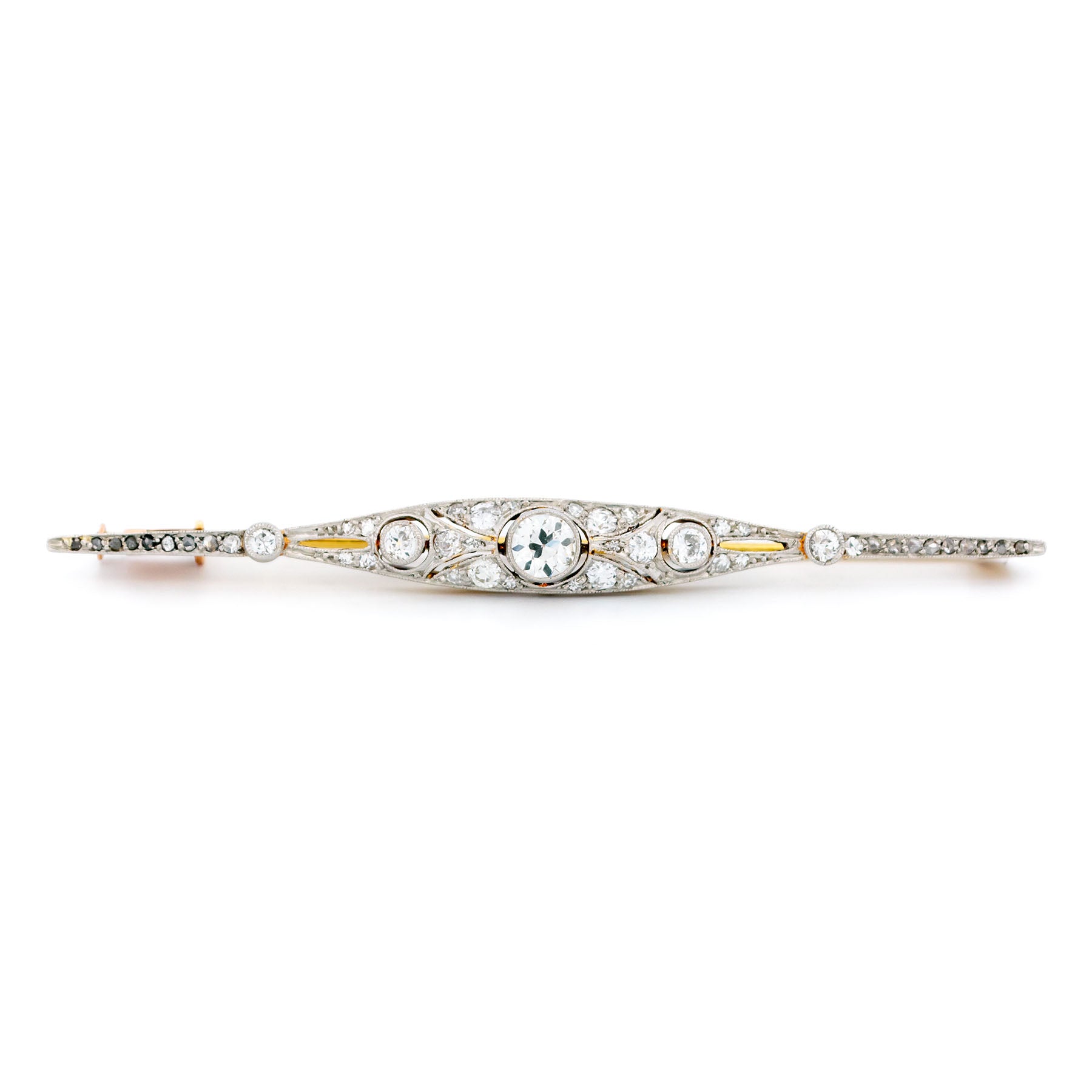A diamond bar brooch in gold and platinum, on a white background