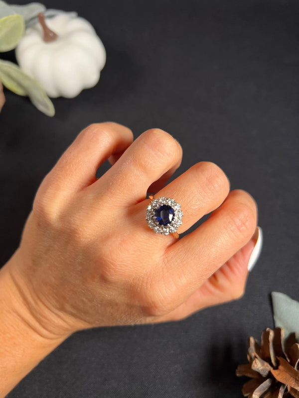 A round sapphire and diamond cluster ring, modelled on a hand