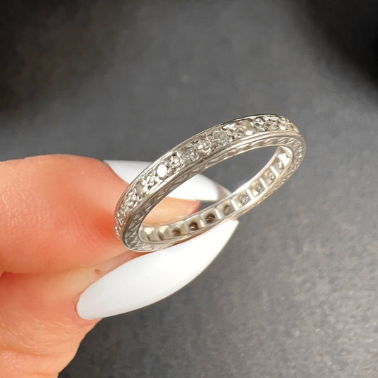 A full eternity ring in white gold, set with diamonds, held in a hand