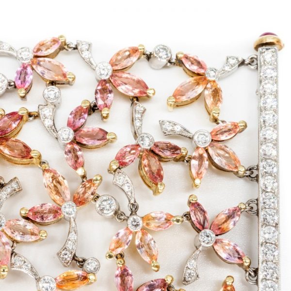 Padparadscha Sapphire, Diamond and Ruby Bracelet; set with 39.52cts pink, orange and red, marquise-cut padparadscha sapphires, decorated with 6.14cts round brilliant-cut diamonds. Accented with cabochon-cut ruby set terminals on the clasp. Mounted in platinum and 18ct yellow gold