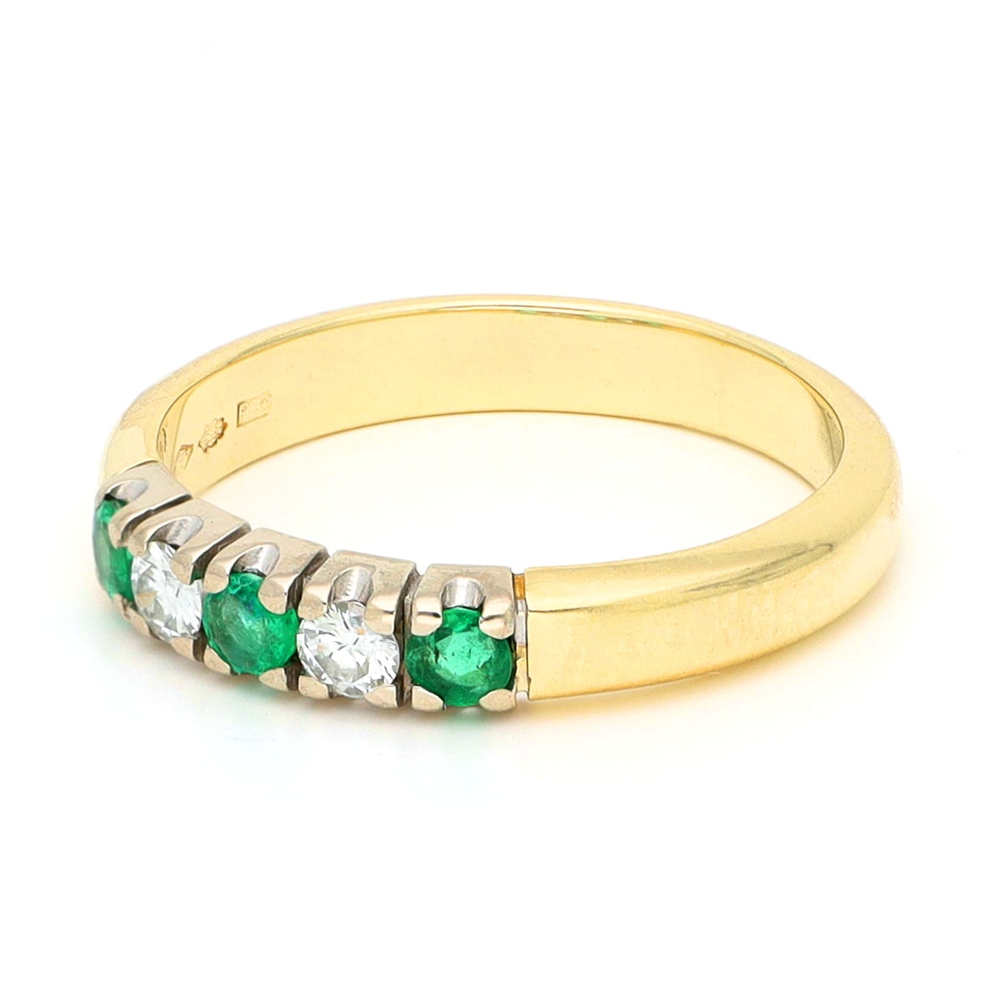 A yellow and white gold five stone ring with emeralds and diamonds, against a white background