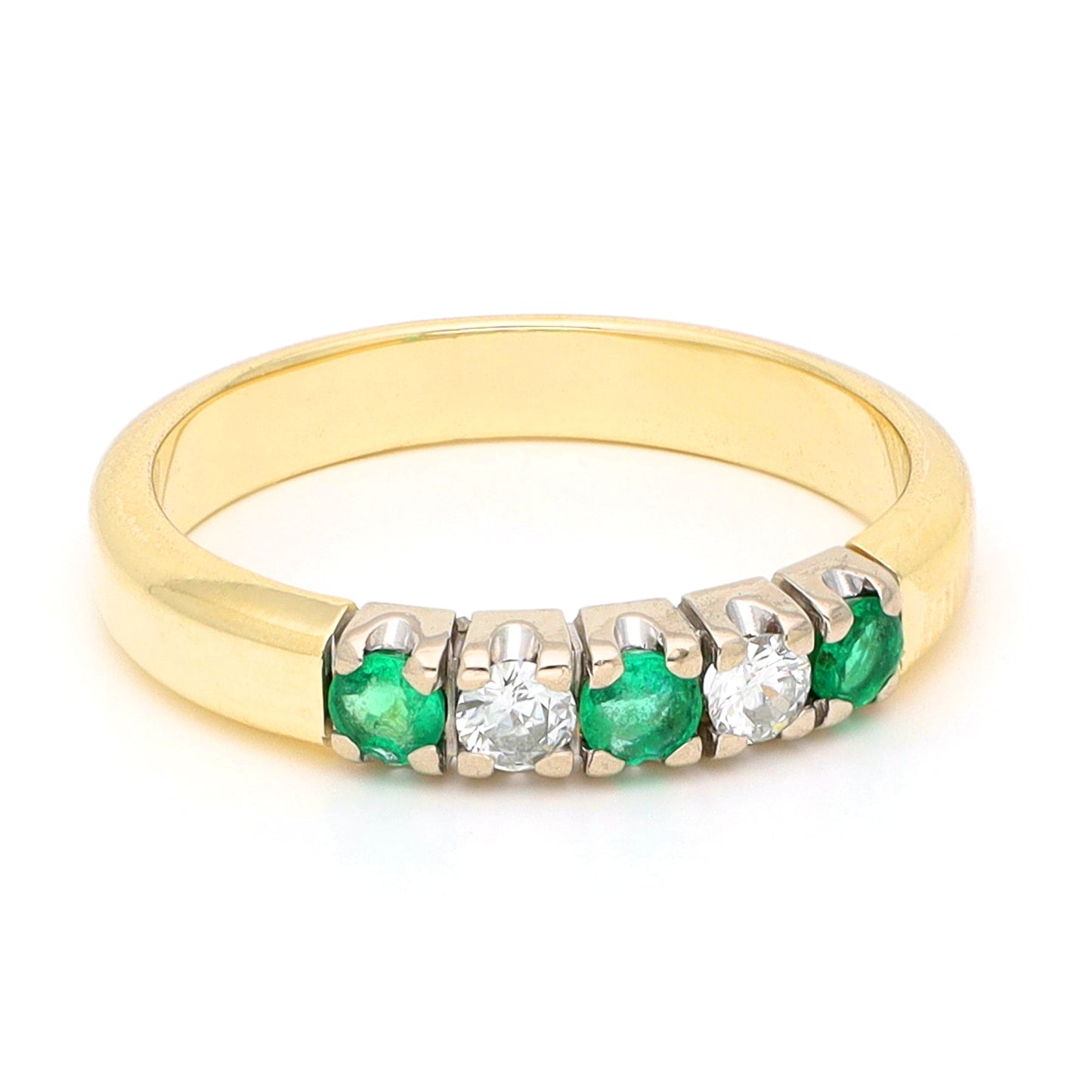 A yellow and white gold five stone ring with emeralds and diamonds, against a white background