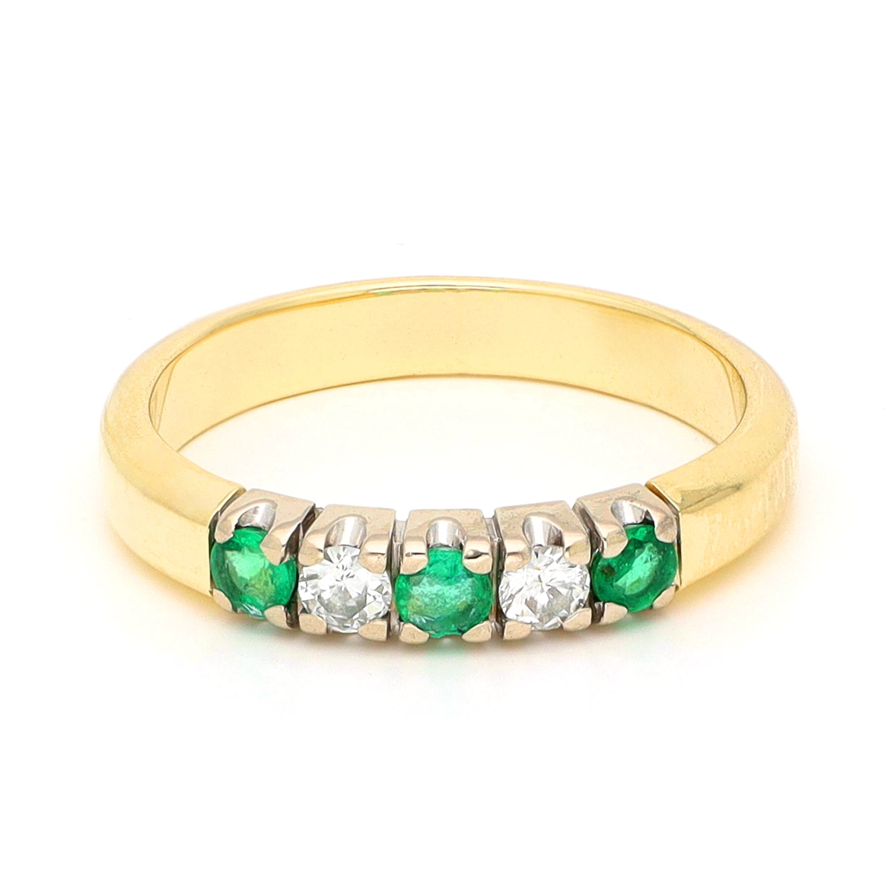 A yellow and white gold five stone ring with emeralds and diamonds, against a white background