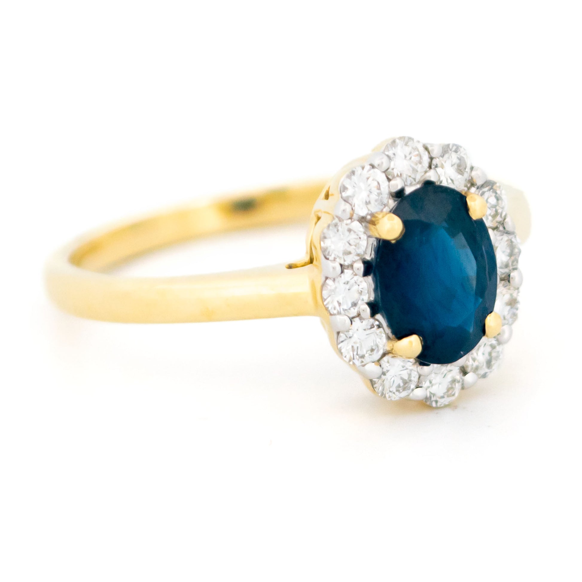 An oval sapphire and round diamond cluster ring in yellow and white gold, against a white background