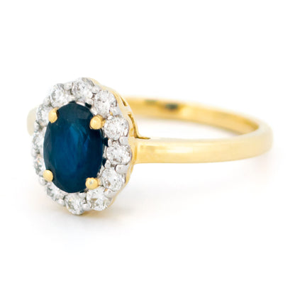 An oval sapphire and round diamond cluster ring in yellow and white gold, against a white background