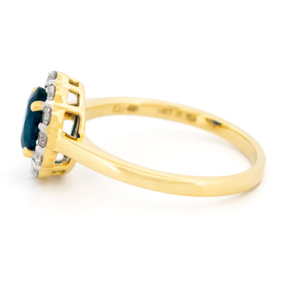 An oval sapphire and round diamond cluster ring in yellow and white gold, against a white background