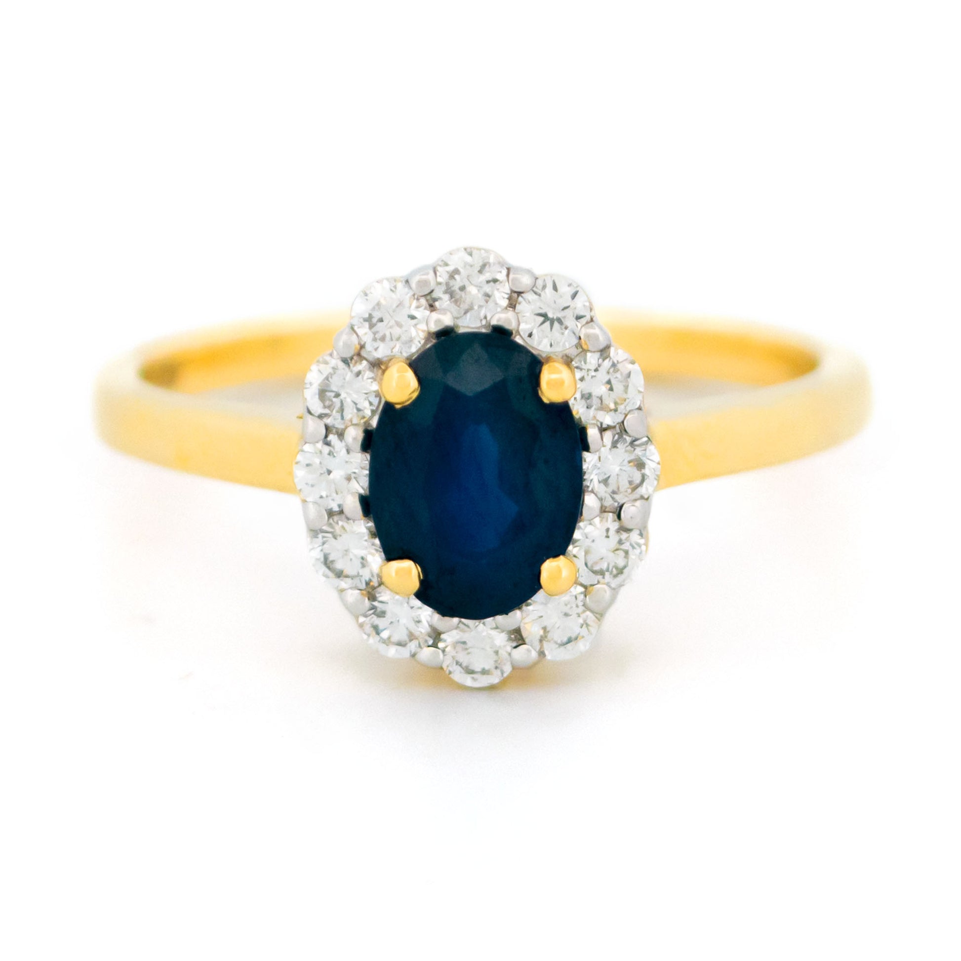 An oval sapphire and round diamond cluster ring in yellow and white gold, against a white background