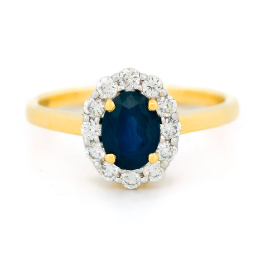 An oval sapphire and round diamond cluster ring in yellow and white gold, against a white background