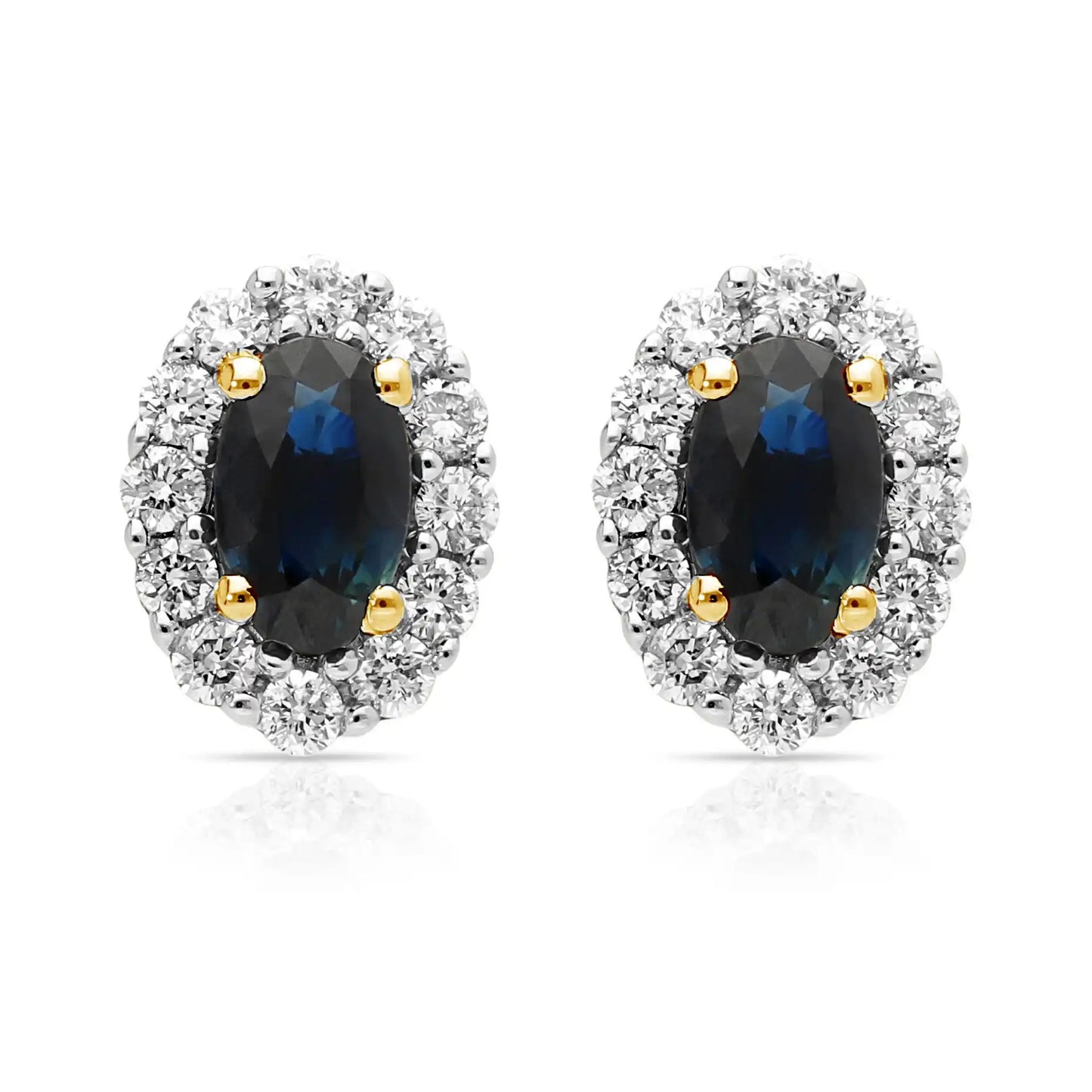 A pair of oval shaped sapphire and diamond cluster earrings in yellow and white gold, against a white background