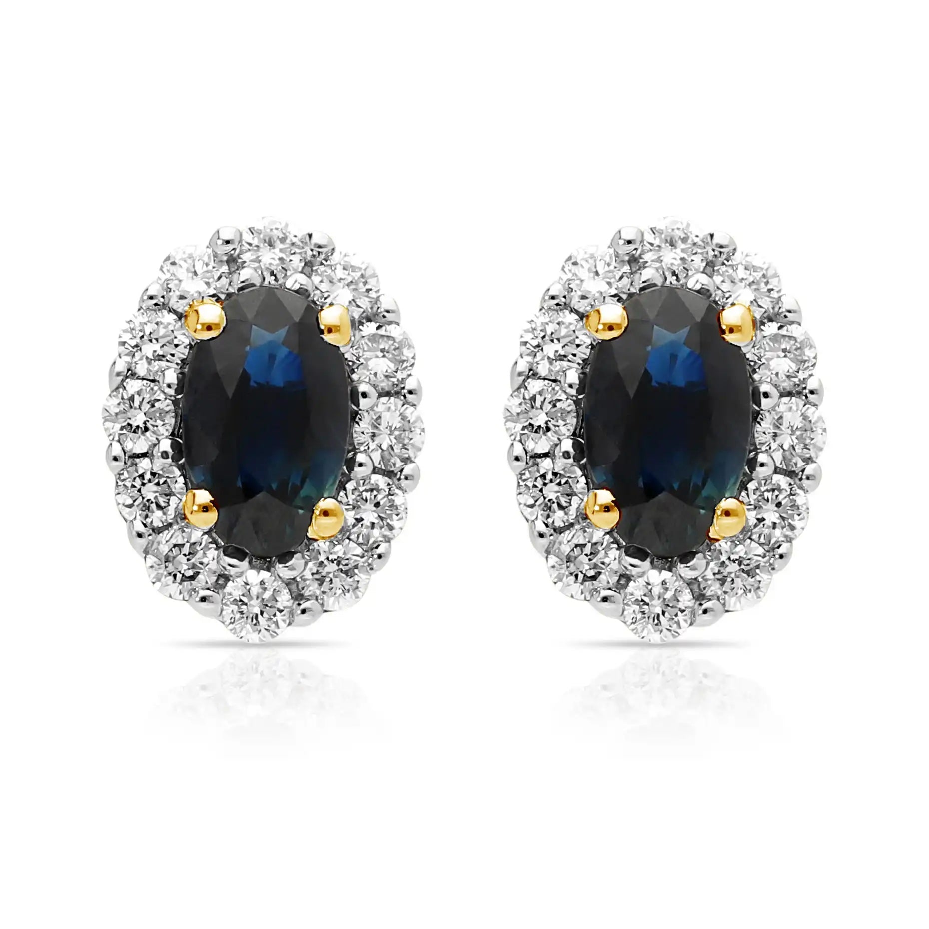 A pair of oval shaped sapphire and diamond cluster earrings in yellow and white gold, against a white background