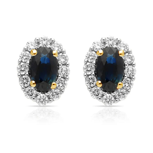 A pair of oval shaped sapphire and diamond cluster earrings in yellow and white gold, against a white background