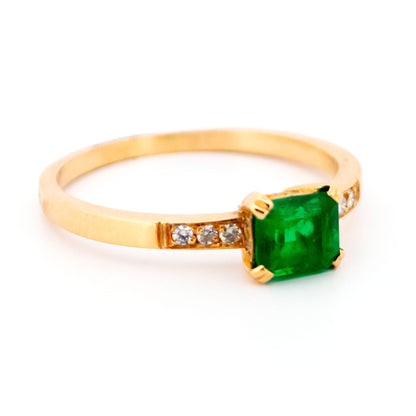 A step cut emerald ring with diamond shoulders, in yellow gold