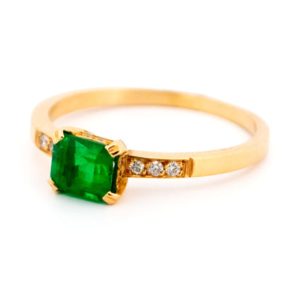 A step cut emerald ring with diamond shoulders, in yellow gold